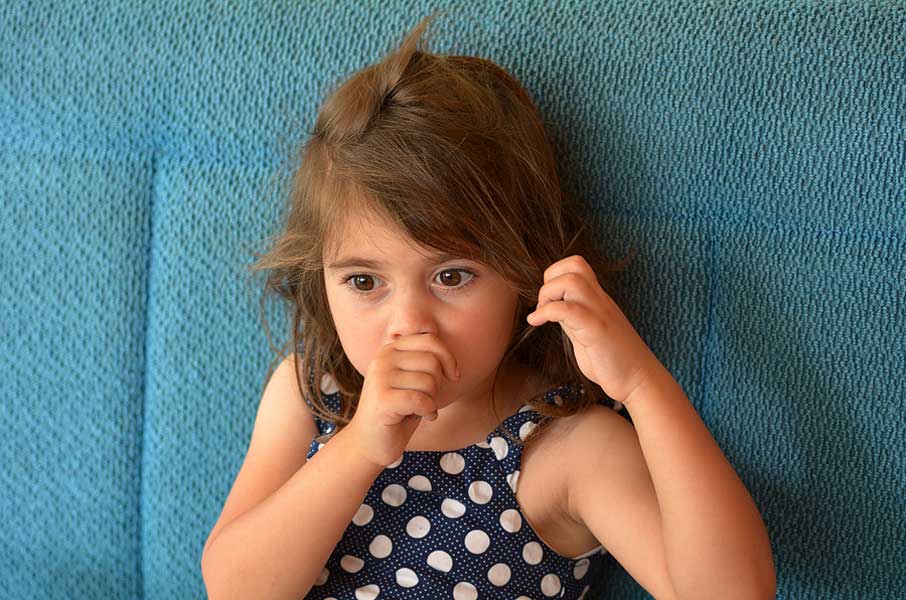 Young female child sucking her thumb while fidgeting nervously with her hair