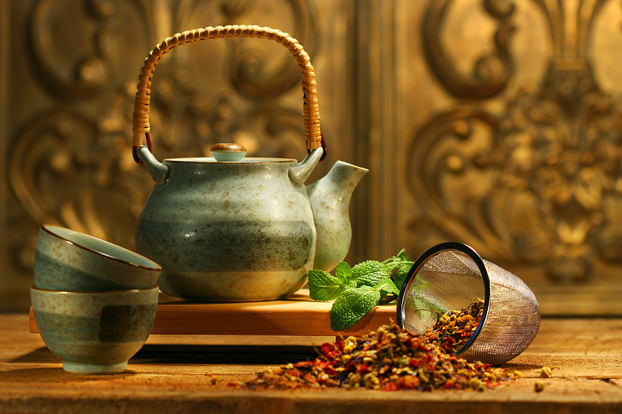 A tea pot and cups on a wooden table.