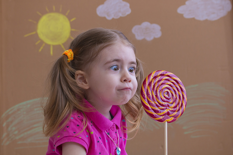 A child stares in amazement at a large lollipop.