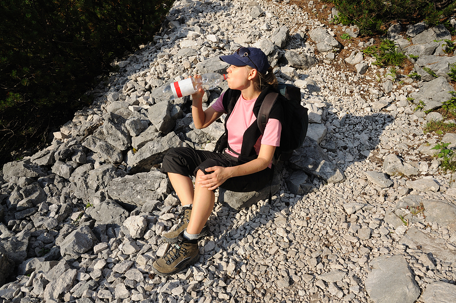 A thirsty hiker drinks water from a bottle