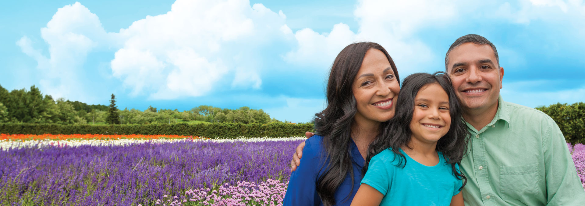 Mother, father and daughter smiling in a field of flowers.